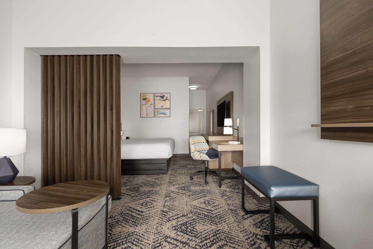 Una habitación de hotel con cama, escritorio, silla y una mesita.