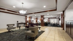A spacious lobby with a glass coffee table, sofas, and a dining area with tables and chairs.