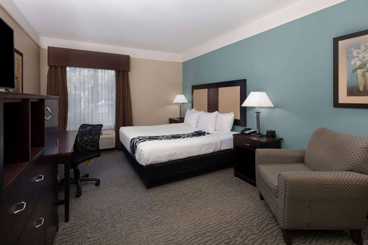 Habitación de hotel con cama, escritorio, silla y sofá.