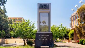 A sign for Arizona State University with a clear view of the campus buildings in the background.