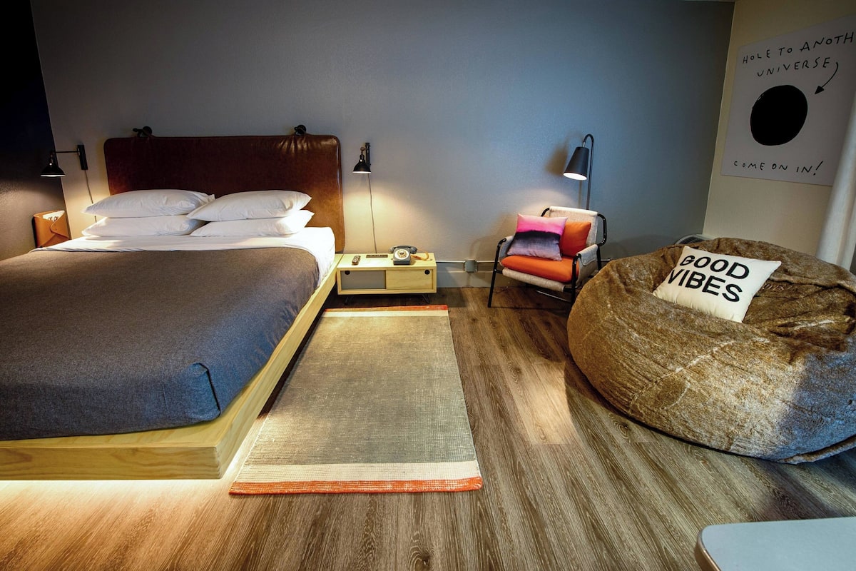 A bedroom with a bed, bedside tables, a reading chair, and a bean bag.