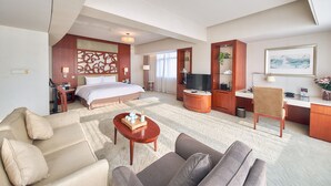 A hotel room with a bed, a sofa, a coffee table, a desk, a TV, and a bathroom. - Parkview Hotel Shanghai (Shanghai)