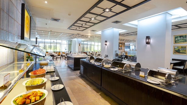 A buffet area with various food stations, including a fruit display and a grill. - Pinnacle Lumpini Park Hotel (Bangkok)