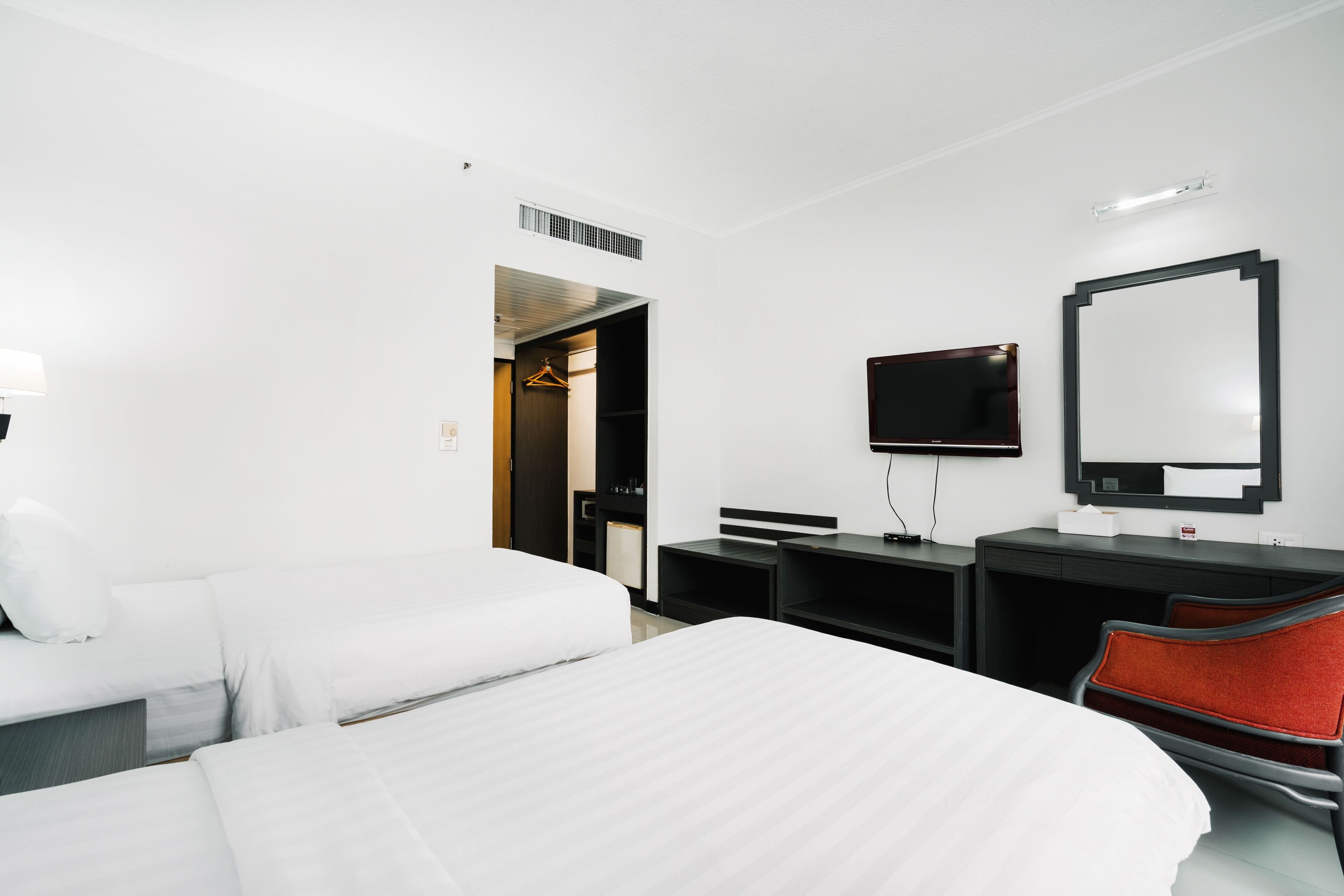 Una habitación de hotel con dos camas, un televisor, un escritorio y una silla.