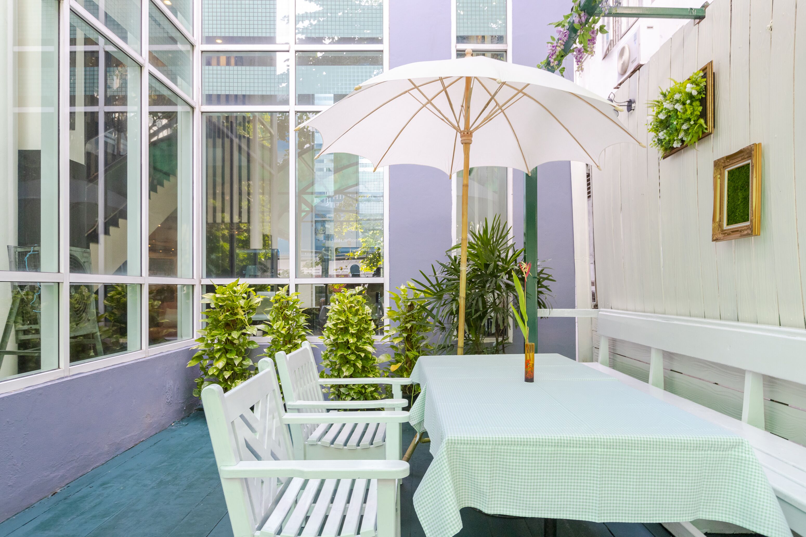 A white table with a checkered tablecloth, a white chair, and a white umbrella.