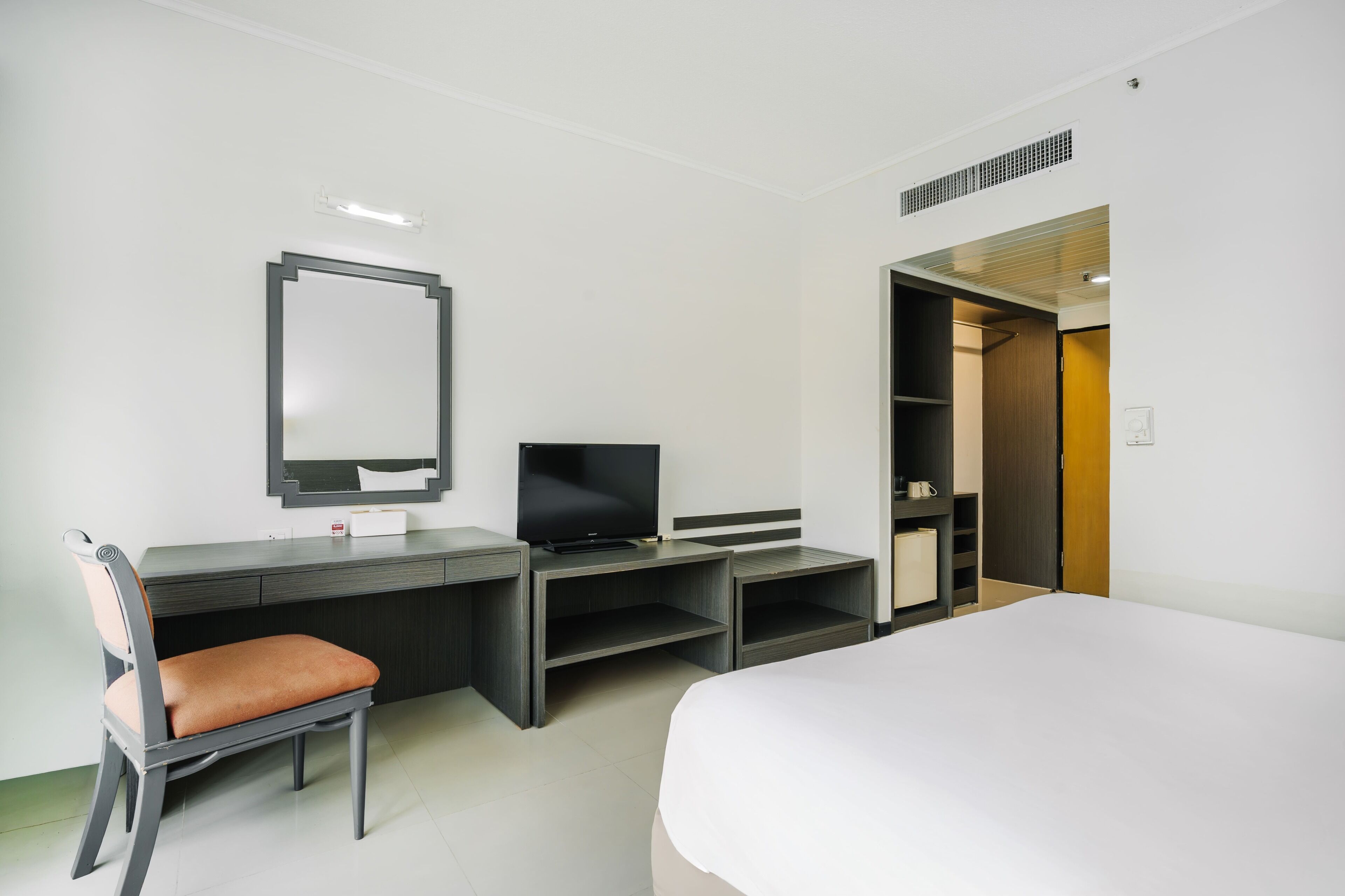 Una habitación de hotel con cama, escritorio con televisor, silla y armario.