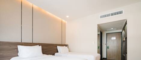 Habitación de hotel con dos camas, suelo de madera, diseño moderno y una puerta que da a otra habitación.