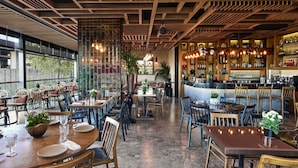 A restaurant interior with wooden ceiling beams, tables with chairs, a bar area with shelves of bottles, and potted plants. - Gezi Hotel Bosphorus, Istanbul, a Member of Design Hotels - Special Class (Istanbul)