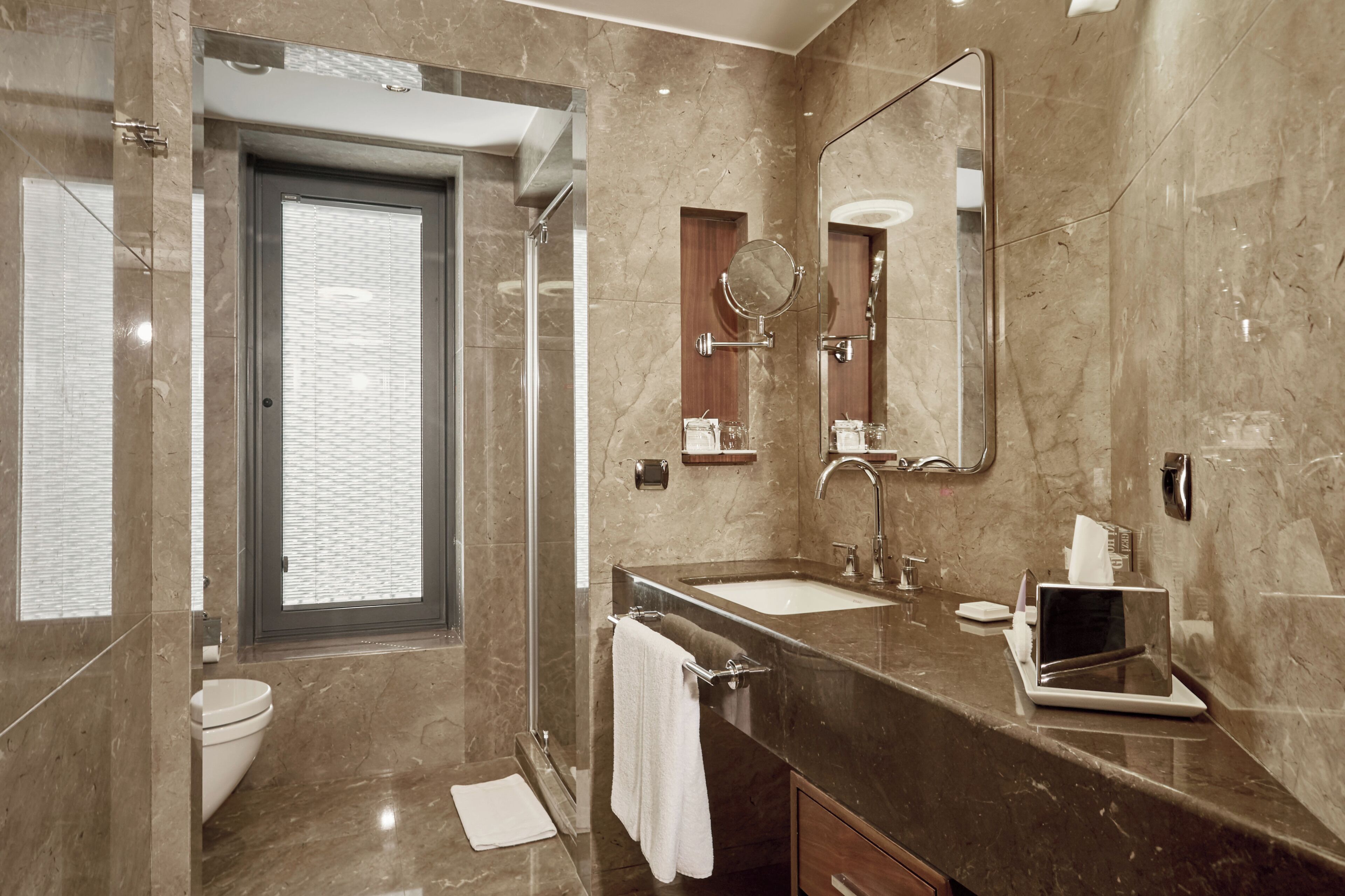 A modern bathroom with a large mirror, a sink, a toilet, and a shower area.