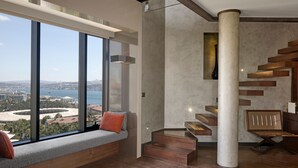A modern interior with a large window offering a city view, a built-in bench with cushions, and a unique staircase design. - Gezi Hotel Bosphorus, Istanbul, a Member of Design Hotels - Special Class (Istanbul)
