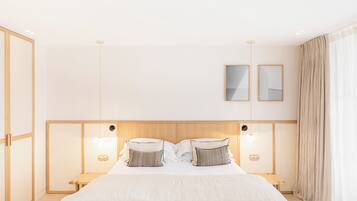 Une chambre d’hôtel moderne dotée d’un grand lit, de tables de chevet et d’une tête de lit avec éclairage intégré.