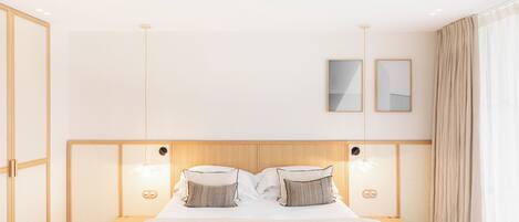 A modern hotel room with a large bed, bedside tables, and a headboard with integrated lighting.