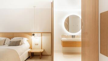 Un dormitorio moderno con cama, mesita de noche y un espejo redondo sobre el lavabo.