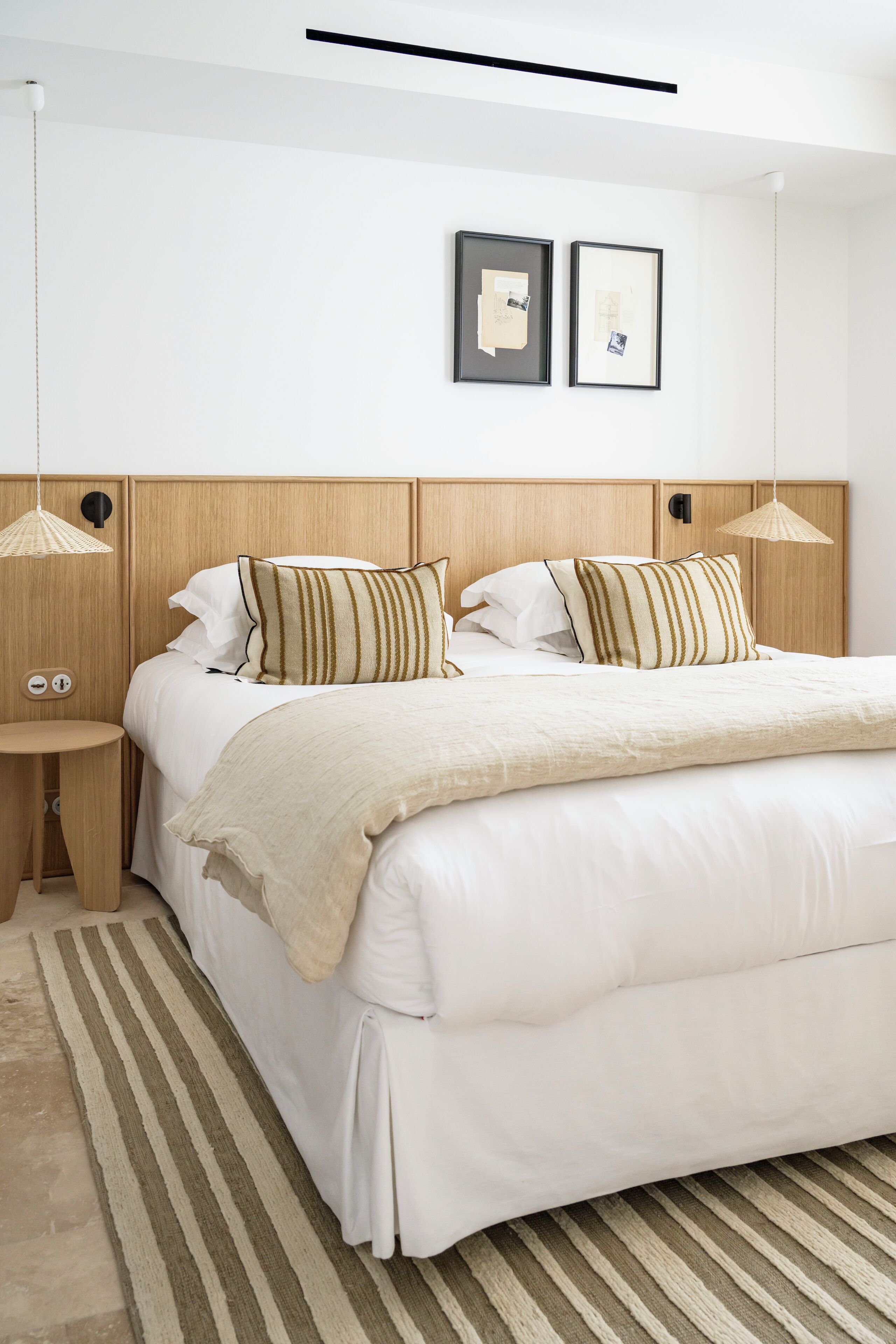 Une chambre à coucher bien rangée, avec un grand lit, deux tables de chevet et un luminaire suspendu.