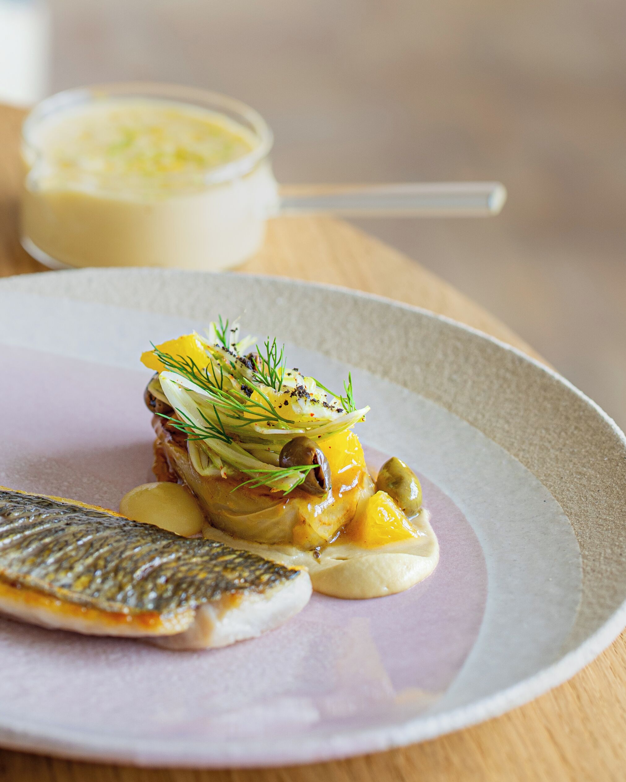 Un plato con pescado, verduras y salsa cremosa.