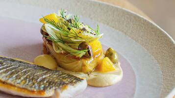 Un plato con pescado, verduras y salsa cremosa.