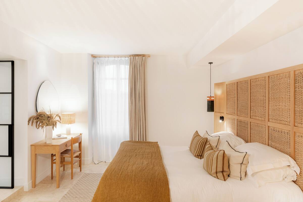 Un dormitorio con cama, mesita de noche, lámpara y escritorio con silla.