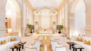 Um lobby espaçoso com área de estar central, tetos altos e arquitetura clássica.