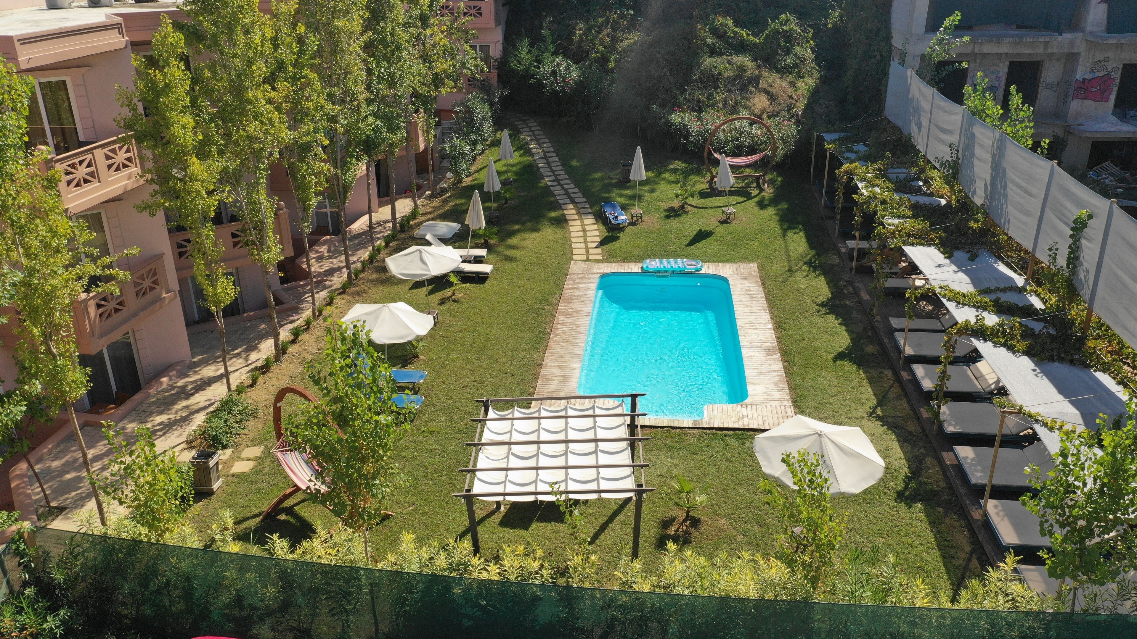 Area piscina sul tetto, con una vasca rettangolare, poltrona relax e ombrelloni.