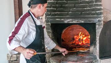 A person operating a brick oven pizza oven.