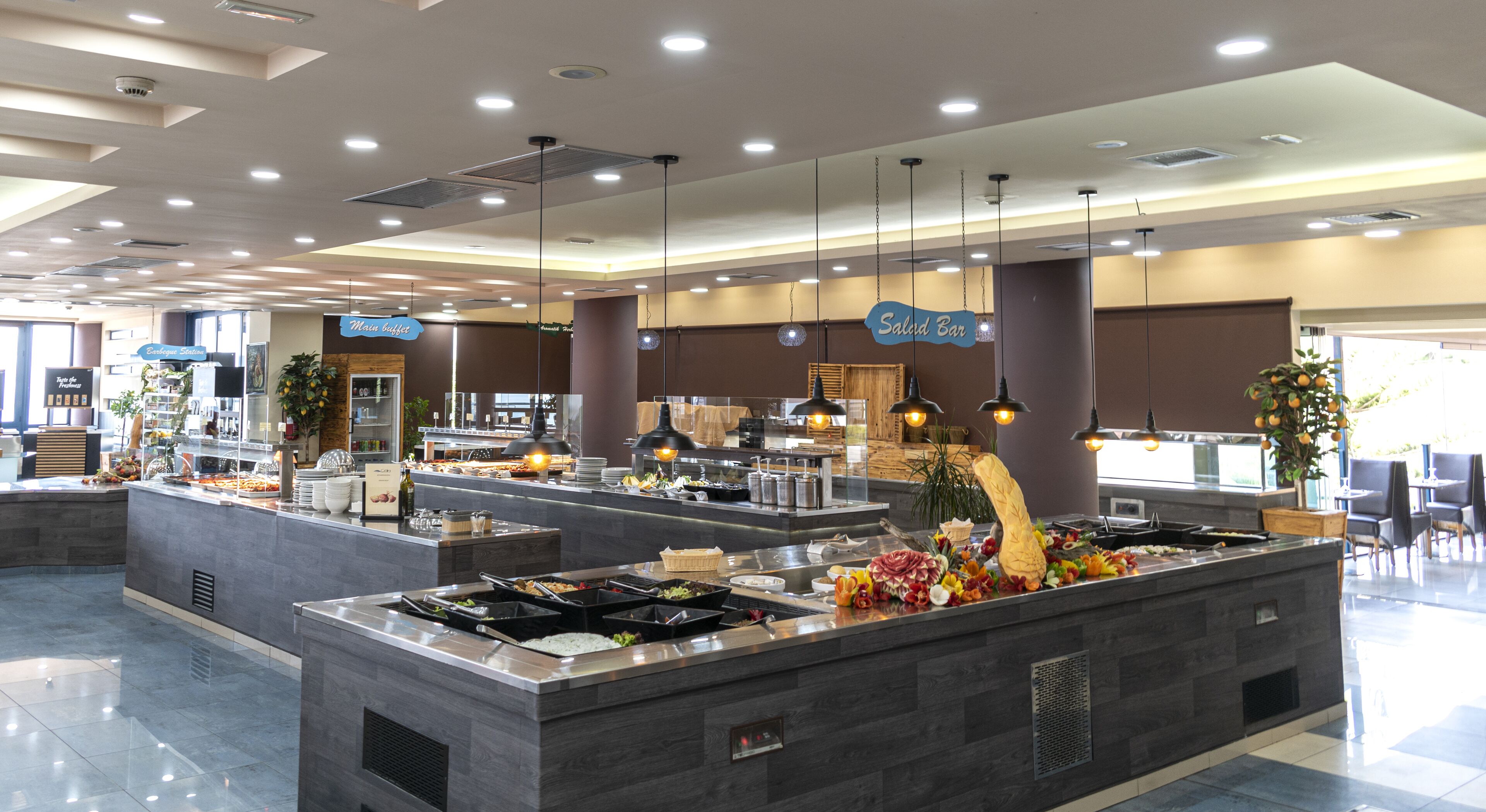A modern buffet area with multiple food stations, including a salad bar, and a coffee station.