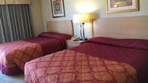 A hotel room with two beds, a nightstand with a lamp, and framed pictures on the wall. - Sands Motel (Riverside)