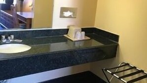 A hotel bathroom with a sink, mirror, towel rack, and a small framed picture on the wall. - Sands Motel (Riverside)