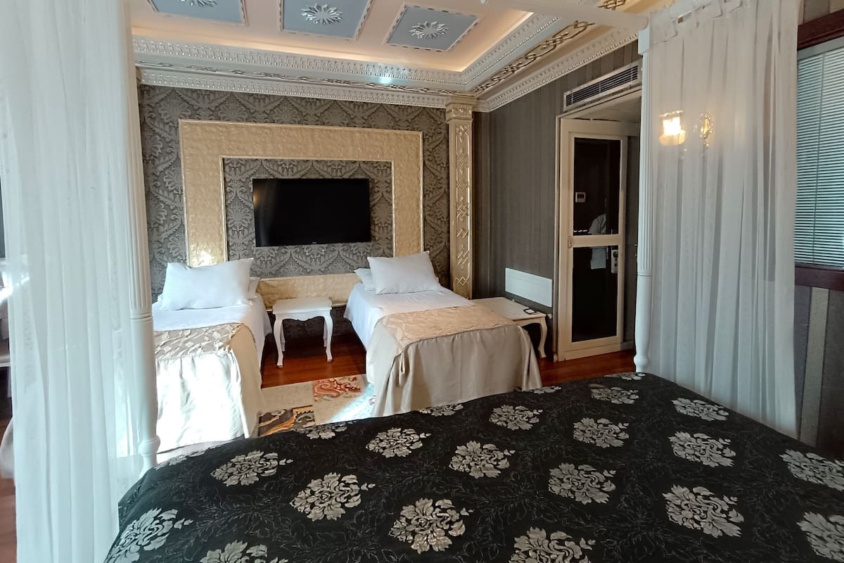 A hotel room with two beds, a TV, a desk, and a wardrobe.