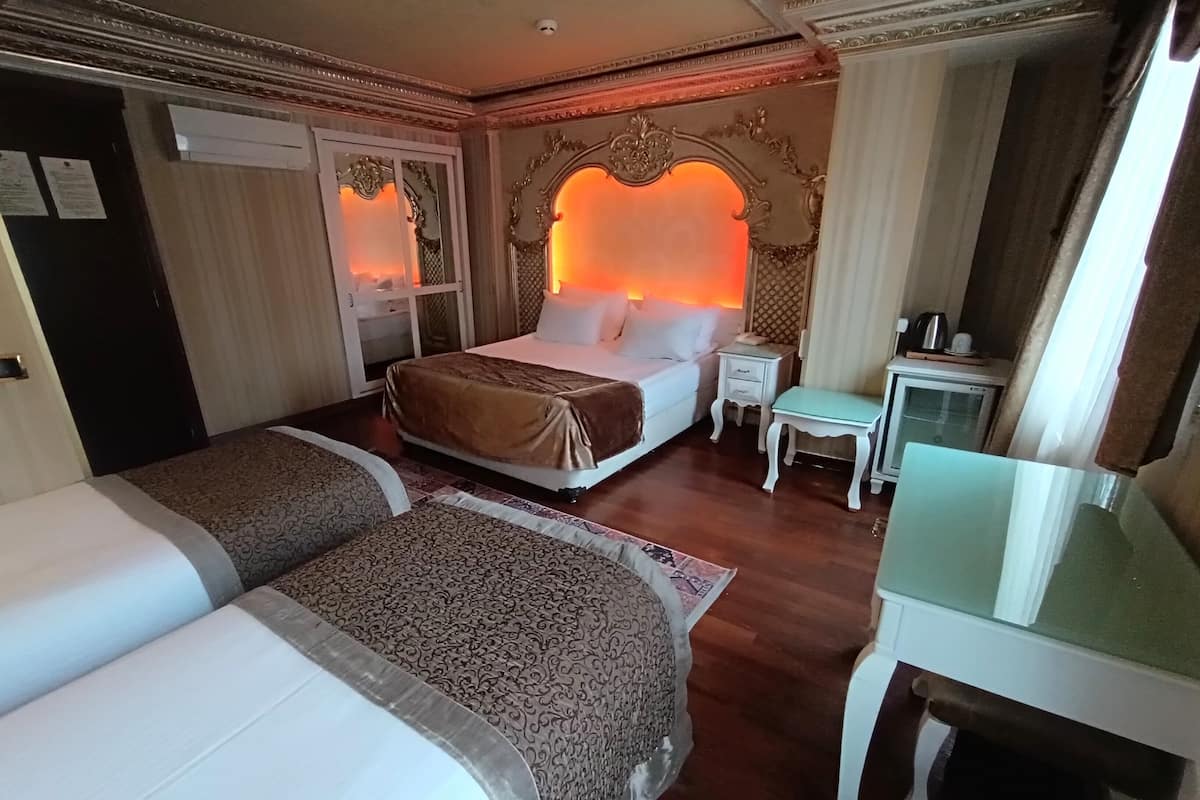 A hotel room with two beds, a desk, a nightstand, and a mirror.