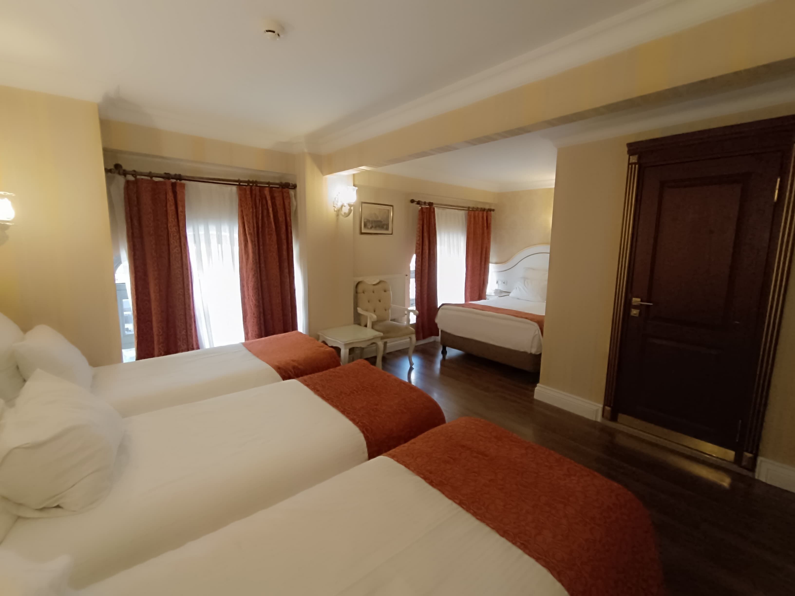 Una camera d'albergo con due letti, una sedia, un tavolino e una porta.