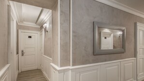 Un pasillo con puertas blancas, un espejo grande y un aplique.