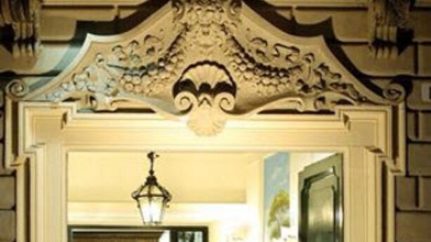 Una entrada imponente con suelo a cuadros, un arco decorativo y una puerta verde.