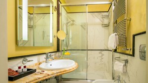 Un baño con ducha envuelta en vidrio, un lavabo con encimera de mármol, una bañera y un bidé.