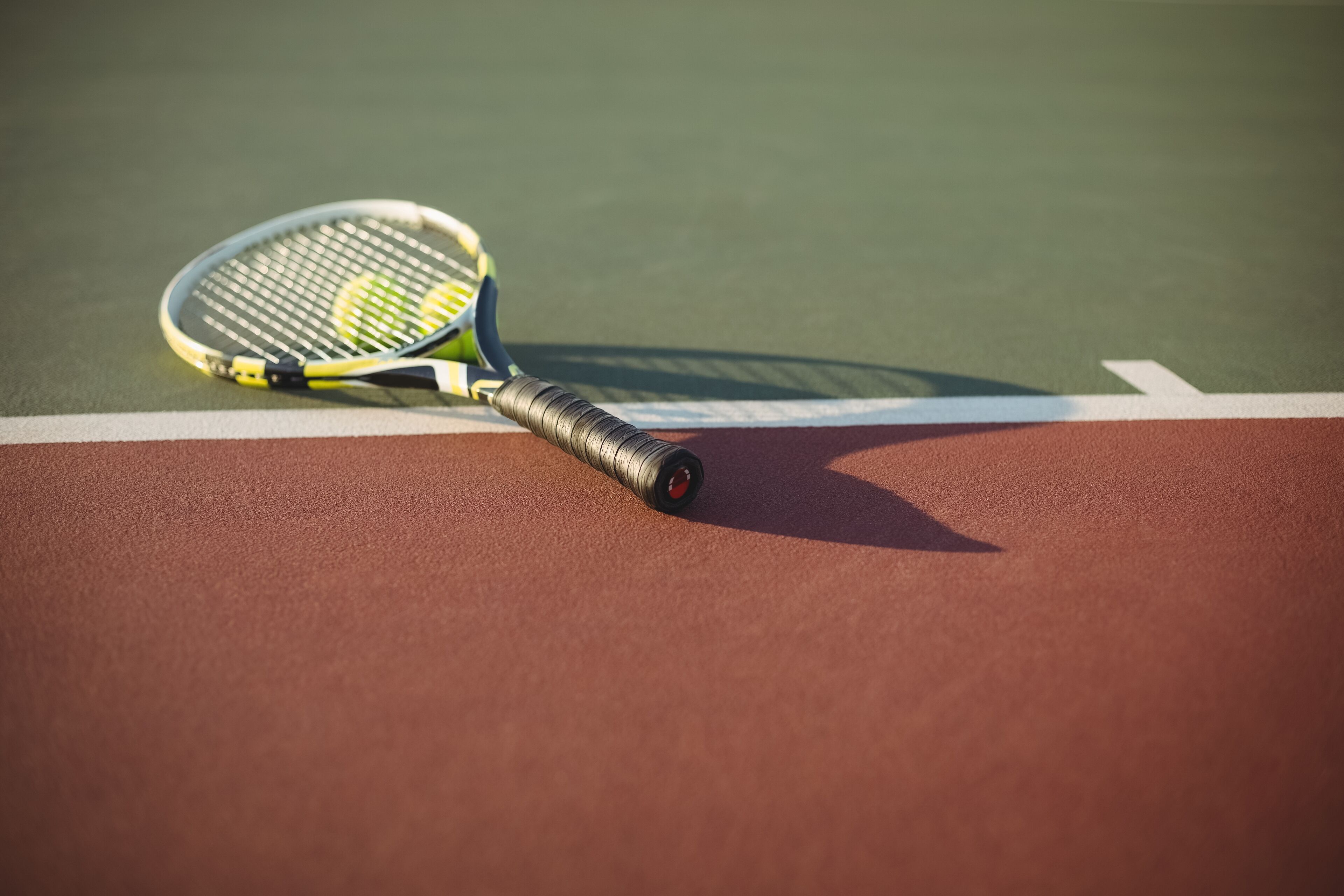 A tennis racket on a court with a red and green surface.