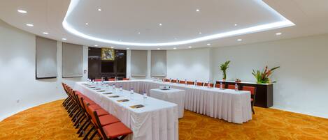 A conference room with a long table, chairs, and a carpeted floor.