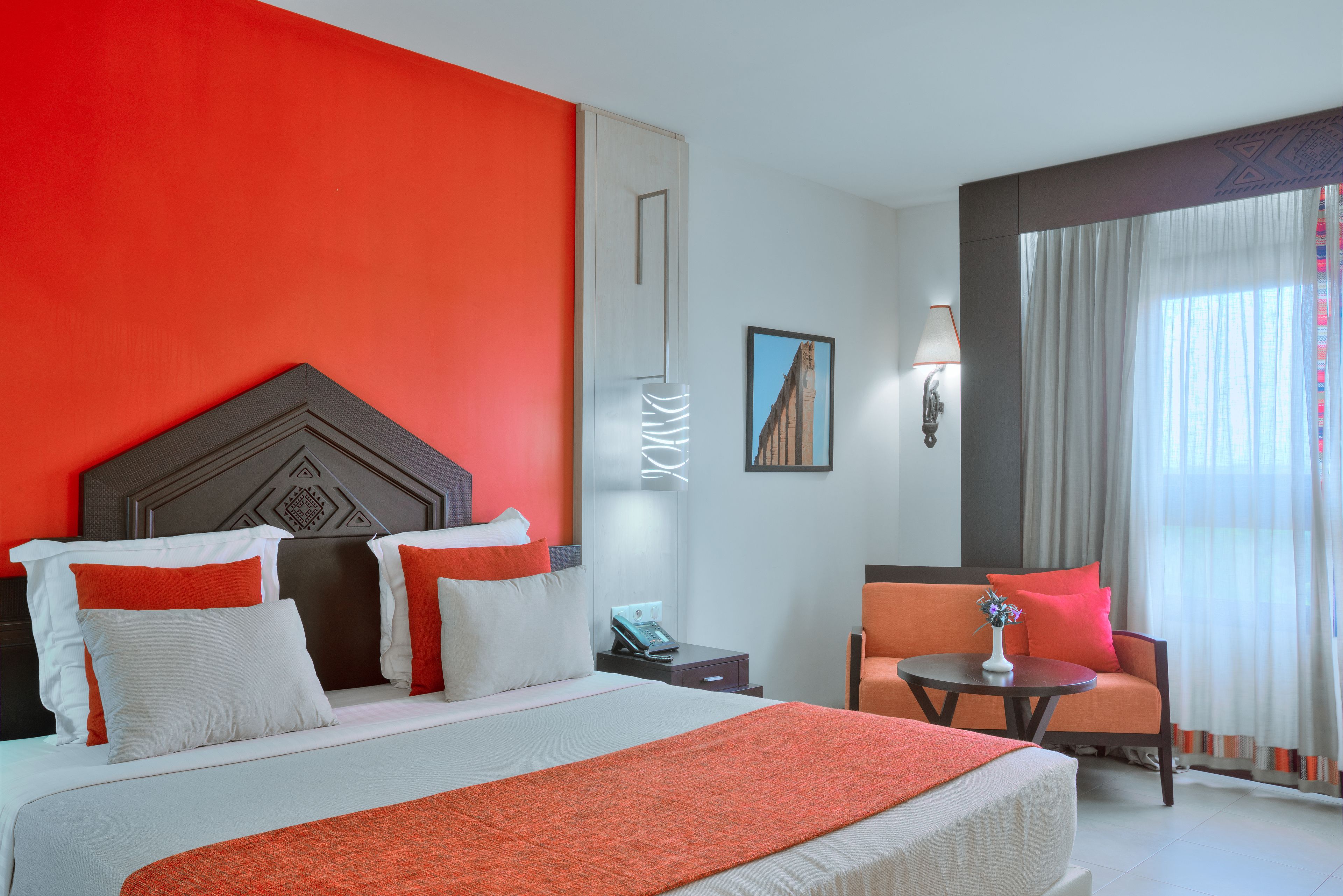 Una habitación de hotel con una cama grande, un sofá, una mesita de noche y una ventana con cortinas.
