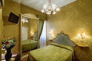 Una habitación de hotel con un espejo grande, una araña y una cama con ropa de cama verde.