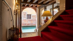 Una escalera con alfombra roja que conduce a una habitación con vistas a un canal y un edificio de ladrillo.