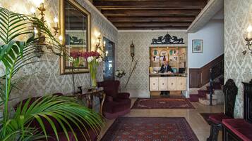 A traditional interior with a wooden staircase, a mirror, a desk, and a bookshelf.