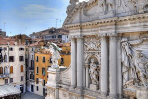 A street view with a classical building featuring ornate sculptures and columns.
