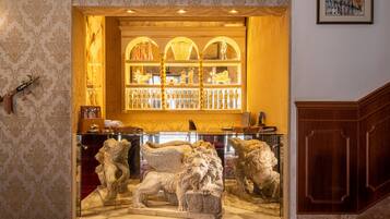 A bar area with a glass display case containing a lion statue and a collection of bottles.