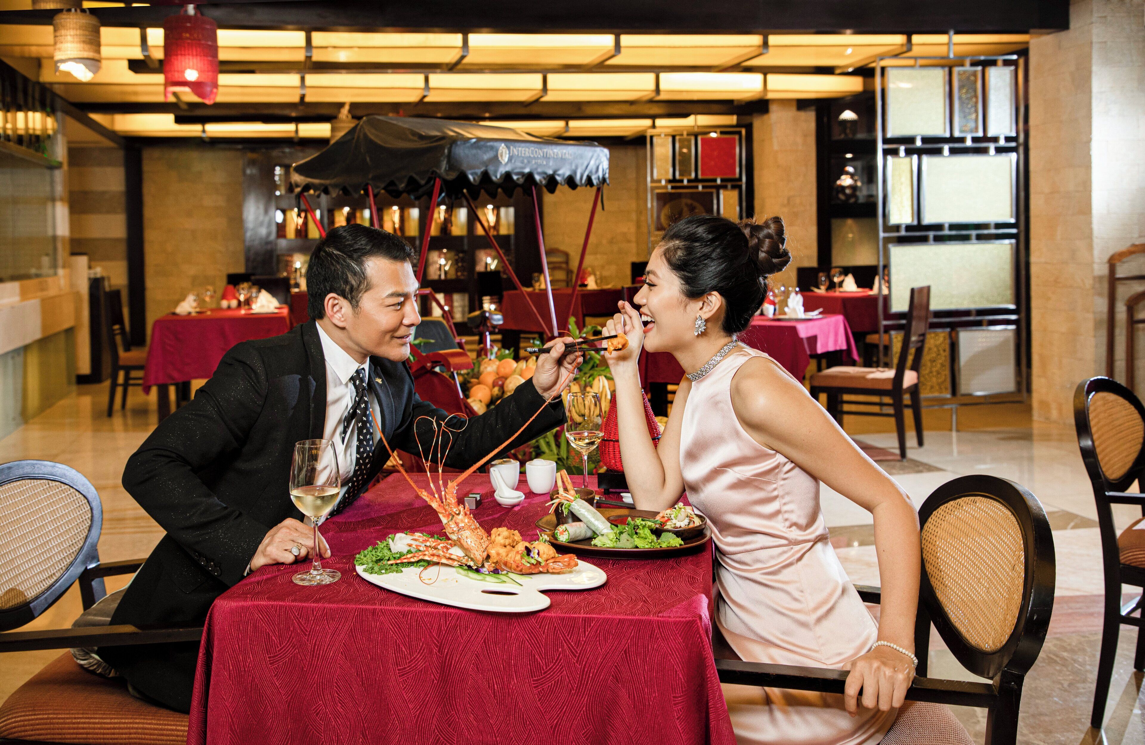 A dining table with a lobster, wine glasses, and plates of food.