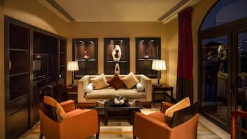 A modern living room with a sofa, two armchairs, a coffee table, and decorative items on shelves.