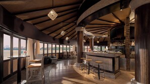 A bar area with a curved counter, stools, and a view of the city through large windows. - InterContinental Hanoi Westlake by IHG (Hanoi)