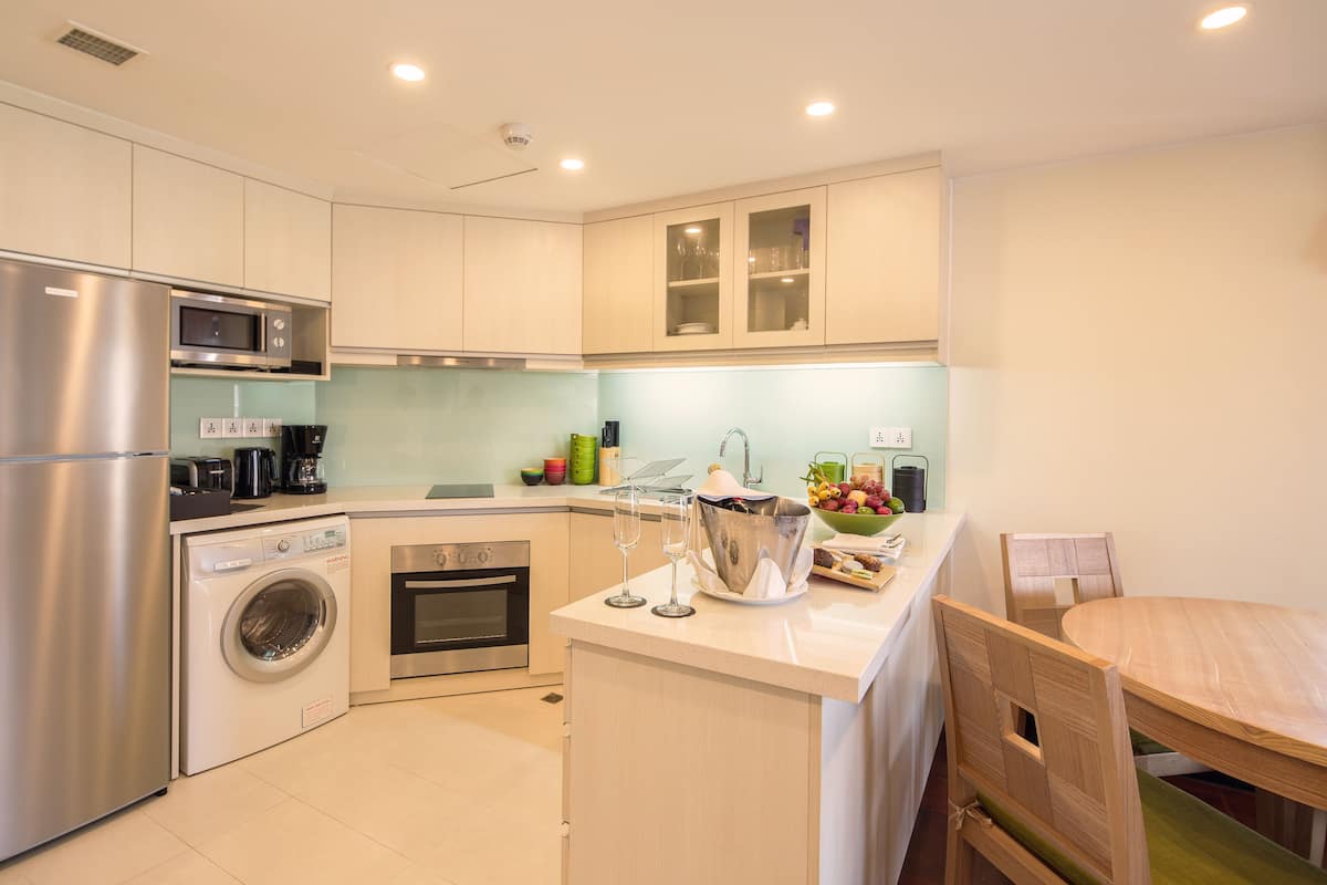 A modern kitchen with stainless steel appliances, a built-in washing machine, and a dining area with a wooden table and chairs.