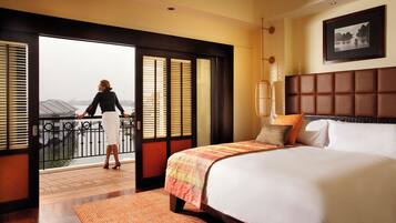 Une chambre d’hôtel avec un grand lit, une vue sur un plan d’eau et un balcon doté d’une balustrade.