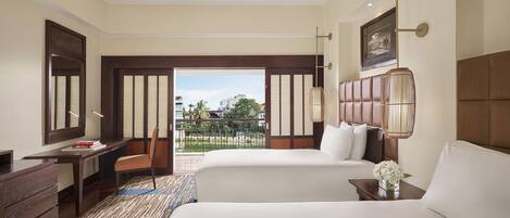 A hotel room with two beds, a desk, a chair, a large window, and a view of the outdoors.