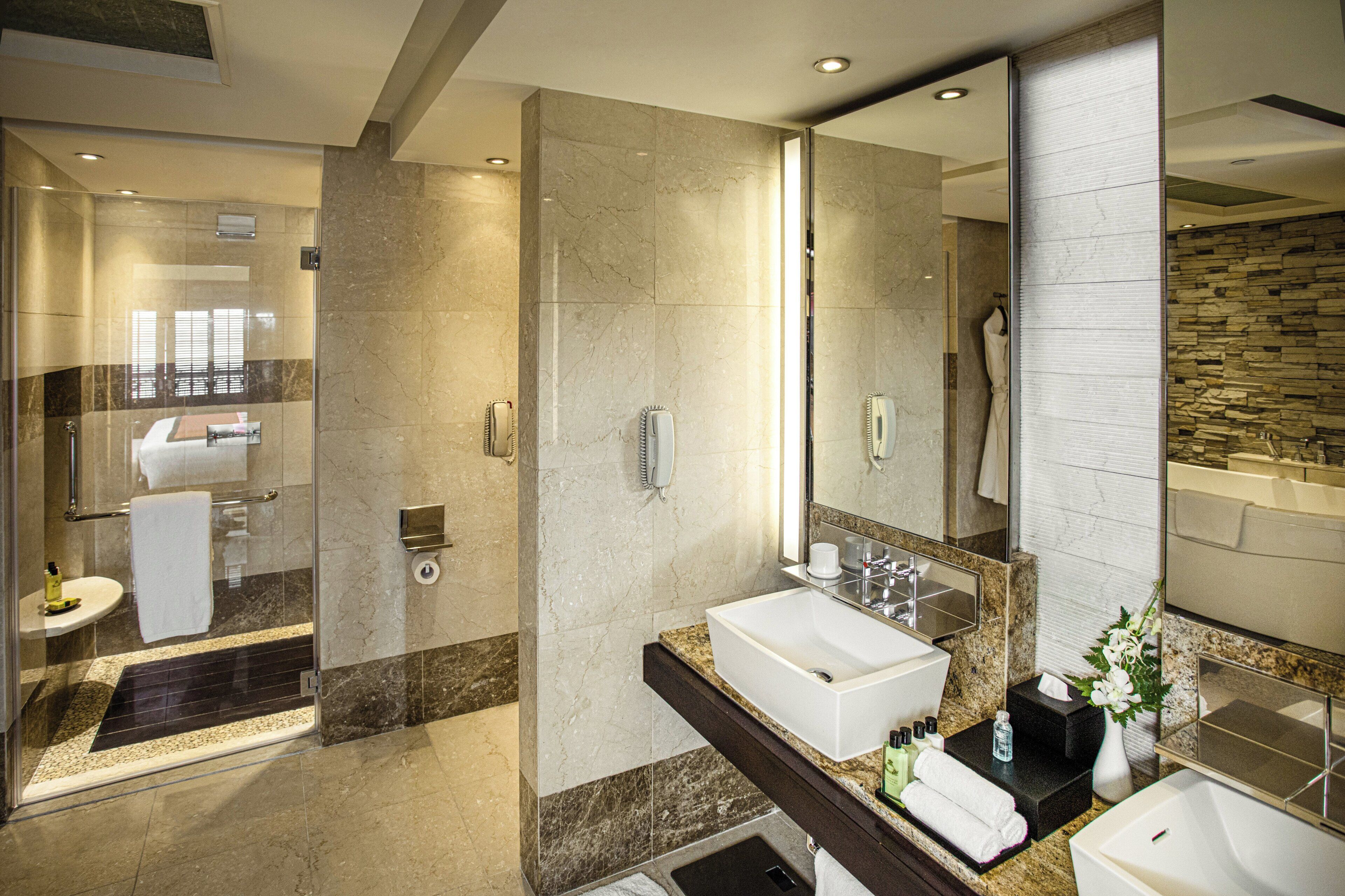 Un baño moderno con cabina de ducha de vidrio, tocador doble y un espejo grande.