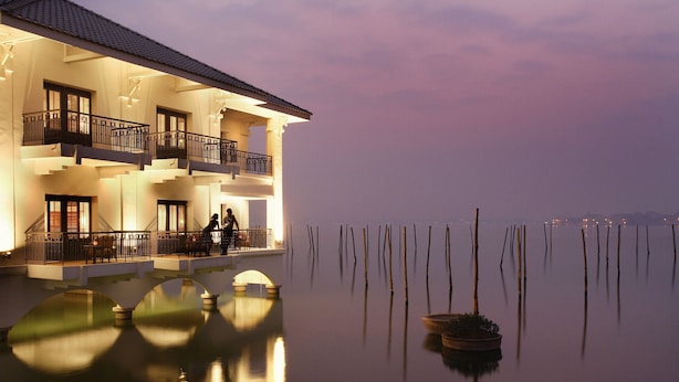 A multi-story hotel with balconies, a pool area, and a view of the water.