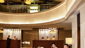 A modern hotel lobby with a curved ceiling, a reception desk, seating area, and a staircase. - InterContinental Hanoi Westlake by IHG (Hanoi)
